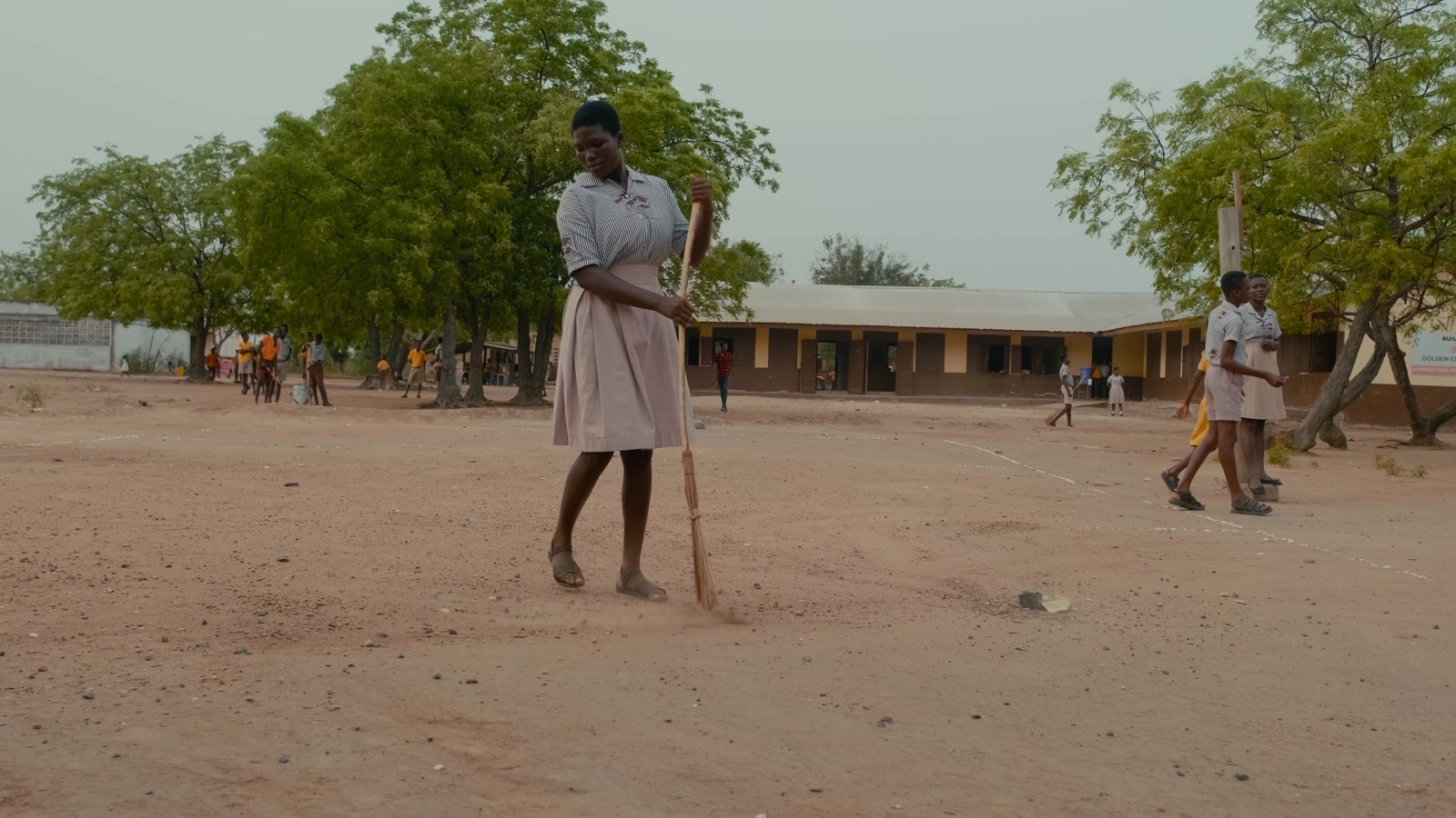 A schoolgirl sweeping the schoolyard