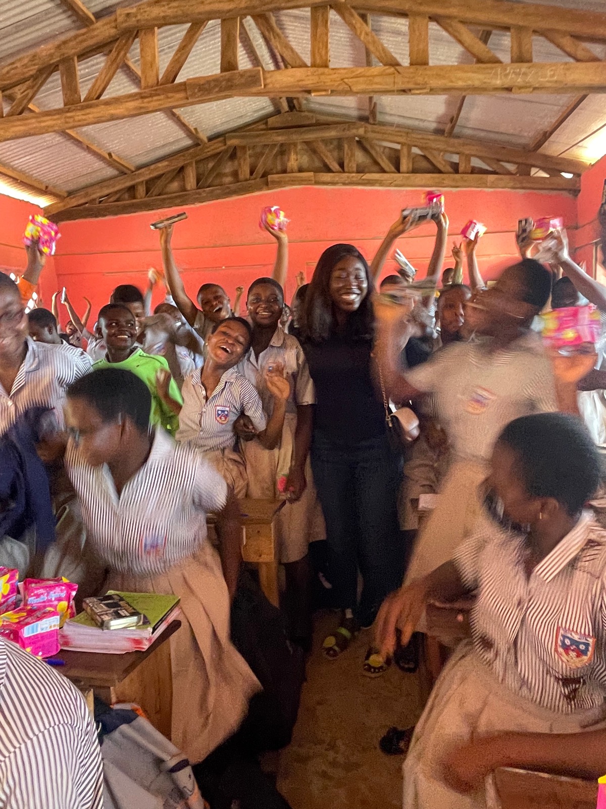 Schoolgirls joyfully holding up sanitary pads during a session